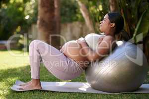 Fit mom, healthy baby. a pregnant woman working out with a stability ball outside.