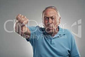No I dont like that at all. a unhappy older man giving the thumbs down in a studio against a grey background.