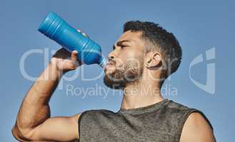Woking up a thirst after an intense workout. Low angle shot of a sporty young man drinking water while exercising outdoors.