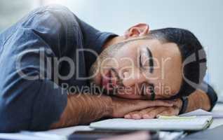 Maybe all my problems will disappear when I wake up. a young businessman feeling exhausted and sleeping on his desk in his office.