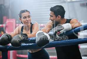 Fit, active and healthy boxing team bonding after workout, training and exercise in a wellness center. Sporty, athletic or strong man and woman on break from kickboxing fight and sports match in ring
