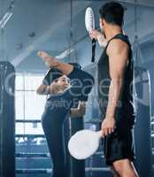 Kickboxing, combat and fighter woman training high kicks with her coach in the gym. Female athlete performing martial arts and training, exercising or doing a workout for a fight with her trainer