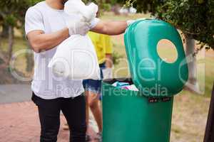 A new path leaves no clean hands. a man throwing trash in a bin outdoors.