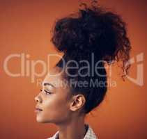 The bigger the bun, the bigger the dreams. a young woman wearing her hair in a bun against an orange background.