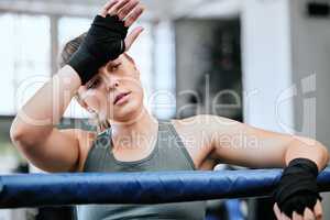 Active, fit and tired female athlete sweating, thinking and taking a break after a routine workout for fitness at the gym alone. One serious, sporty and sweaty woman resting after a cardio exercise