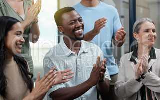 Staying inspired and in high spirits. a young businessman applauding with his colleagues in an office.