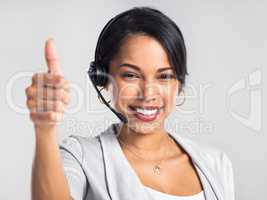 Consider your request taken care of. Studio shot of a young businesswoman using a headset and giving a thumbs up against a grey background.