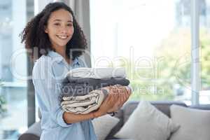 Neatly folded clean laundry is so satisfying. a young woman holding a pile of clean folded laundry.