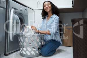 Nothing like a fresh clean load of washing. a young woman preparing to wash a load of laundry at home.