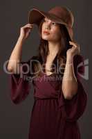 Its the perfect summer hat. an attractive young woman posing in studio against a grey background.