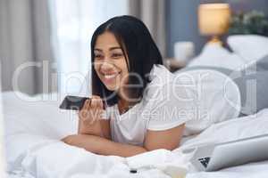 Learn to laugh everyday. a young woman watching television from the comfort of her warm bed.