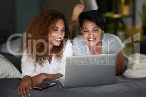 Do you think we should subscribe. a young couple using a laptop while lying on their bed.