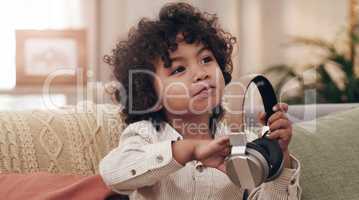 Song suggestions anyone. an adorable little boy listening to music on headphones while sitting on a sofa at home.