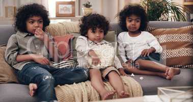 Sharing is caring. three adorable little boys eating popcorn and watching movies together at home.