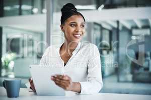 Believe it is yours and youre halfway there. an attractive young businesswoman sitting alone in her office and using a digital tablet.