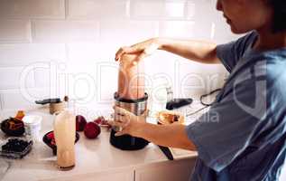 Time to get those vitamins in. a young woman blending up fresh fruit in her kitchen at home.