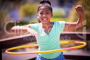 Stay physically fit and have lots of fun doing it. Portrait of a cute young girl playing with a plastic hoop at the park.