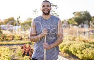 Today is a beautiful day to garden. a young man holding a gardening tool on his farm.