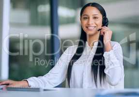 Our customers are at the core of our organization. a young woman using a headset and computer in a modern office.