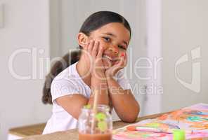 Painting is a great play activity for children of all ages. an adorable little girl painting while sitting at a table.