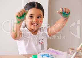 The messier it gets, the more fun it is. an adorable little girl sitting at home with water-based paint smeared on her hands.