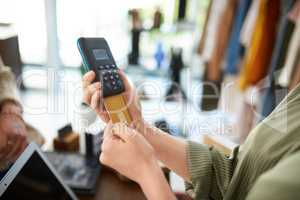 Spoil yourself a little. a woman using a card machine while doing a card payment in a store.