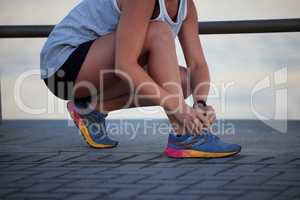 Comfort comes first. a sporty young woman tying her shoelaces while out for a run.