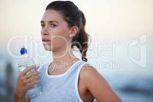 Sometimes you gotta lose your breath to find your heartbeat. a sporty young woman holding a bottle of water while out for a run.