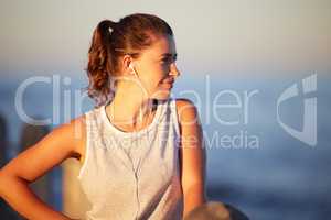 Want to enjoy exercise more Creative a workout playlist. a sporty young woman wearing earphones while out for a run.