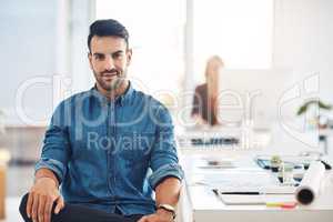 Portrait of a young, trendy and fashionable designer sitting at his office desk. Male creative taking a break at work, next to drawing desk. Expert contemplating ideas for new architectural designs