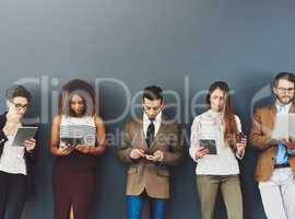 Group or team of business people working and browsing with wireless technology in studio against a grey background. Digital marketing colleagues networking online to advertise a startup company