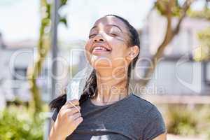 Feels good to fill my lungs with fresh air. a young woman taking off her face mask after going for a run outdoors.