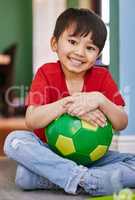 Wanna go outside and kick the ball with me. Portrait of an adorable little boy playing with a soccer ball at home.