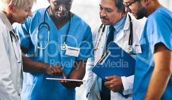 Group of doctors, medical professionals and workers doing reaching on a tablet, browsing on the internet and discussing a health case together at a hospital. Experts talking about a diagnosis