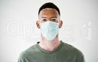 Masks are a simple barrier to help contain the spread. Studio portrait of a young man with vitiligo wearing a mask against a white background.
