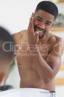 Dab, dab, dab. a handsome young man standing and applying aftershave to his skin in his bathroom.