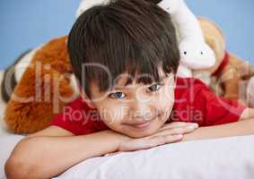 A happy childhood is the most-fortunate gift in life. Portrait of an adorable little boy lying on a bed with his stuffed toys at home.