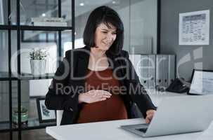 Everything seems to be in order, including my little one. an attractive pregnant businesswoman sitting in her office and using her laptop while holding her tummy.