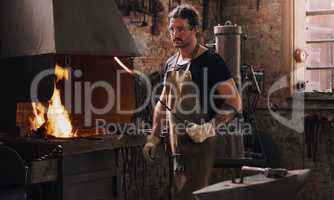 I create in the heat of the moment. a man heating a metal rod in his workshop.