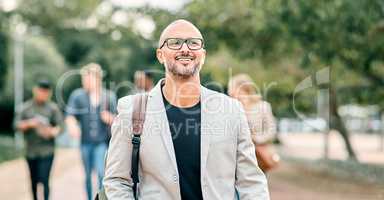 Creativity is intelligence having fun. a confident mature businessman walking through the city with a young team behind him.