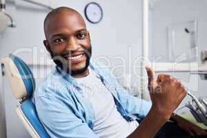 Id recommend this dentist anyday. Portrait of a young man showing thumbs during his dental appointment.