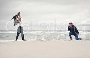 Strike a pose, babe. a man taking pictures of his girlfriend while spending time at the beach.