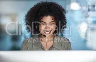 Use youre smile to change the world. a young female agent smiling over her monitor with her headset on while working in a call centre.