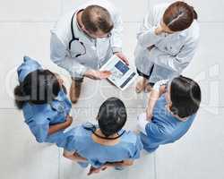 Discussing healthcare plans and programs. High angle shot of a group of medical practitioners using a digital tablet together in a hospital.