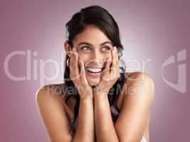 Let life surprise you. a beautiful young woman pondering with her hands rested her chin and face against a pink background.