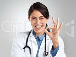 Youll be alright with me by your side. Studio portrait of a young doctor showing an okay gesture against a grey background.