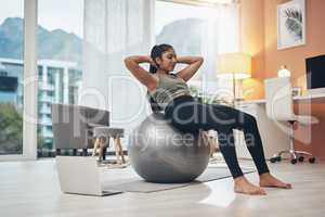 Getting fitter with virtual sessions. a woman working out in her living room with her laptop next to her.