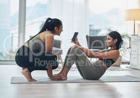 This fitness tool is super helpful. two beautiful young women exercising together at home.