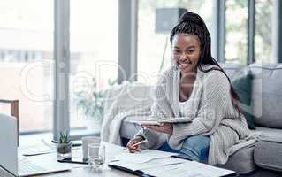 Afford the life of your dreams with good financial planning. Portrait of a young woman going over paperwork and using a laptop on the sofa at home.