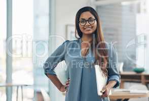 Ready to face the new day with determination. Portrait of a young businesswoman holding a laptop while standing in an office.